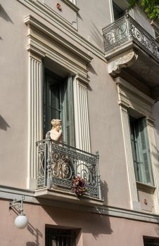 Statue on a wrought iron balcony in ancient district or neighborhood of Plaka in Athens by the Acropolis