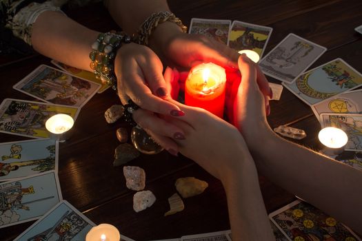 Bangkok,Thailand,March.15.20.Female hands hold a lighted candle in the dark at night. A fortune teller performs a magical. Ritual of enchantment and clairvoyance. Seance and prediction of the future