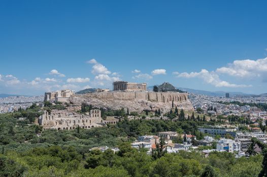 Acropolis and Lycabettus Hill framed by trees from the summit of Lycabettus hill