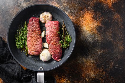 Cooking denver steak on grill frying pan with garlic and herbs just from fire top view with smoke space for text.