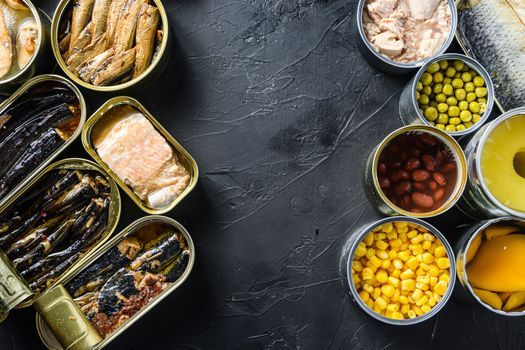 Canned conserve products in tin cans. with fresh organic ingridients Saury, mackerel, sprats, sardines, pilchard, squid, tuna pinapple, corn, peas, mango , beans, over black stone textured background top view space for text side by side concept.