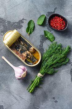 Sardinops in oil in preserve canned food, open can jar woth herbs and garlic ocer grey background top view.