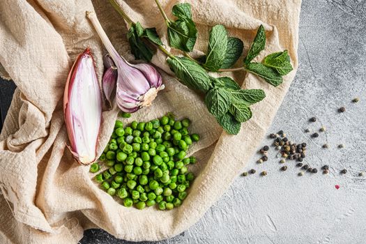 organic green peas for mushypeas and ingredients peas mint shallot pepper and salt keto food photo over grey stone background and cloth top view .