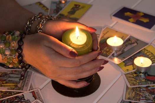 Bangkok,Thailand,March.15.20.Female hands hold a lighted candle in the dark at night. A fortune teller performs a magical. Ritual of enchantment and clairvoyance. Seance and prediction of the future