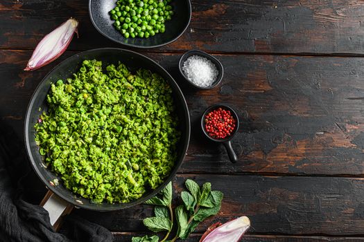 British mushy peas cooked frying pan and peas in bowl with mint shallot pepper and salt over old pub wood surface top view organic keto food space for text.