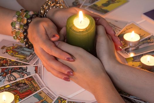 Bangkok,Thailand,March.15.20.Female hands hold a lighted candle in the dark at night. A fortune teller performs a magical. Ritual of enchantment and clairvoyance. Seance and prediction of the future