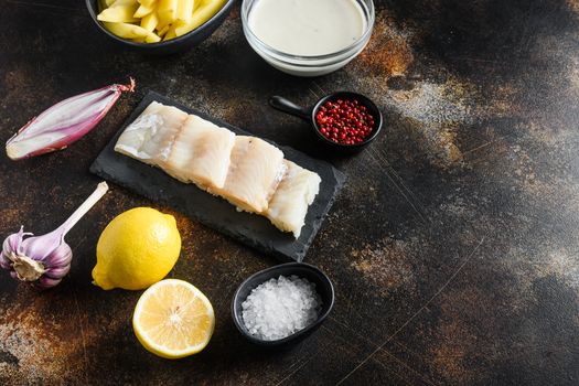 Traditional English Food such as Fish and Chip ingredients raw fish fillet, beer batter, potatoe, shallotgarlic, salt, peppercorns on rustic metal textured surface or table side view space for text.
