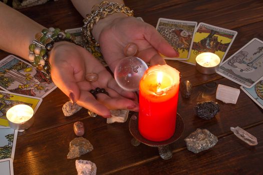 Bangkok,Thailand,March.15.20.The girl holds wedding rings on her hand with Tarot cards with heart,crystals,a magic ball and a lighted candle.Fortune telling for love, the rite of love spell.