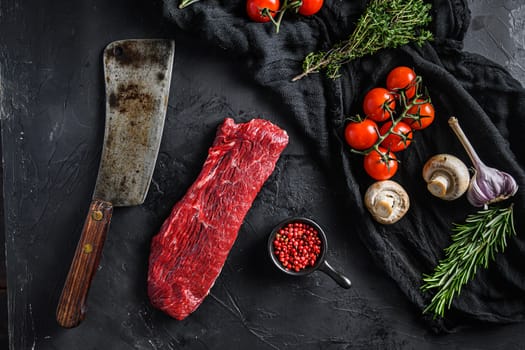 Raw triangle roast or tri tip, near butcher knife with pink pepper and rosemary. Black background. Side view.