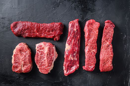 Raw organic meat Top Blade steaks near machete and denver steak, alternative beef cut or Australia wagyu oyster blade on black background top view space for text.