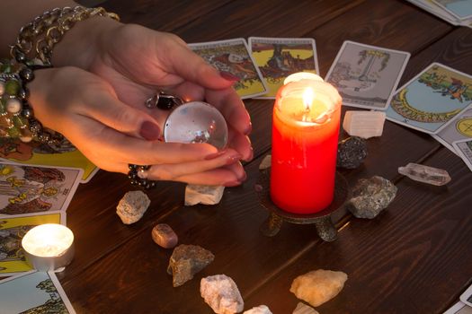 Bangkok,Thailand,March.15.20. A fortune teller holds a magic ball.On the table are fortune-telling cards and lighted candle.Magic sessions with clairvoyance cards.Reading maps by candlelight