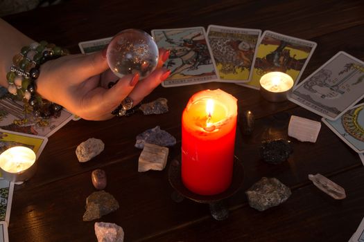 Bangkok,Thailand,March.15.20. A fortune teller holds a magic ball.On the table are fortune-telling cards and lighted candle.Magic sessions with clairvoyance cards.Reading maps by candlelight