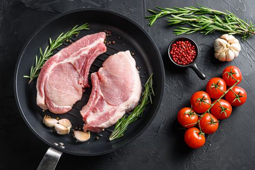 Raw Pork Loin chops in skillet near ingredients wtih herbs pepper and tomatoes top view.