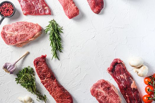 Set of different alternative types of raw beef steaks,on a white stone background top view concept frame in corners space for text in center.