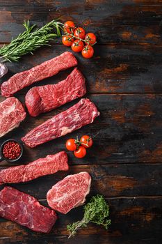 Set of flap flank Steak, machete steak or skirt cut, Top blade or flat iron beef and tri tip, triangle roast with denver cut top view over old butcher wood table vertical space for text.