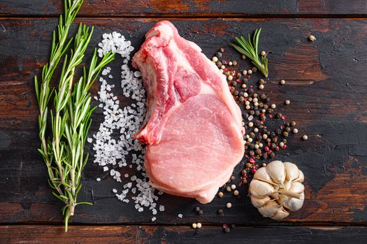Raw meat on dark wood rustic background. Bio organic farm pork steak with herbs and spices. Cooking meat. Copy space. Top view.