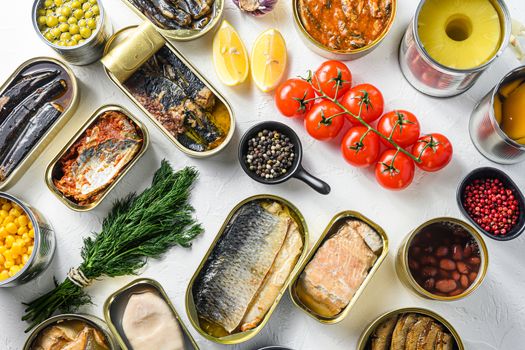 Different canned conserve products in tin cans. with fresh organic ingridients Saury, mackerel, sprats, sardines, pilchard, squid, tuna pinapple, corn, peas, mango , beans, over white textured background top view