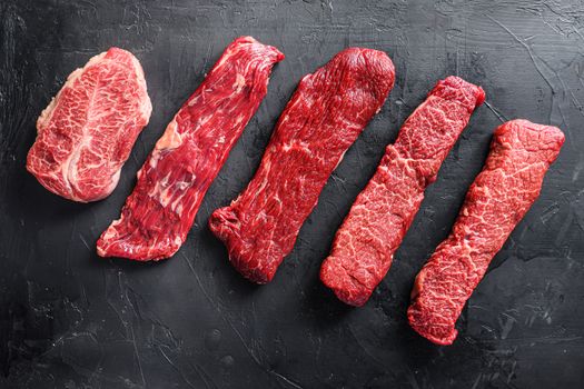 Raw, alternative beef steaks flap flank Steak, machete steak or skirt cut, Top blade or flat iron beef and tri tip, triangle roast with denver cut . Black stone background. Top view