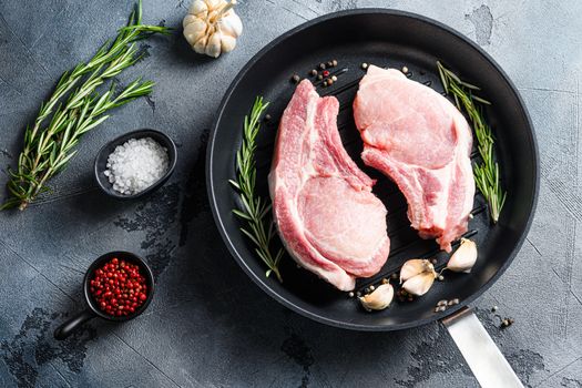 Cutlet on a rib pork in cast iron pan top view with herbs rosemary and rose pepper.