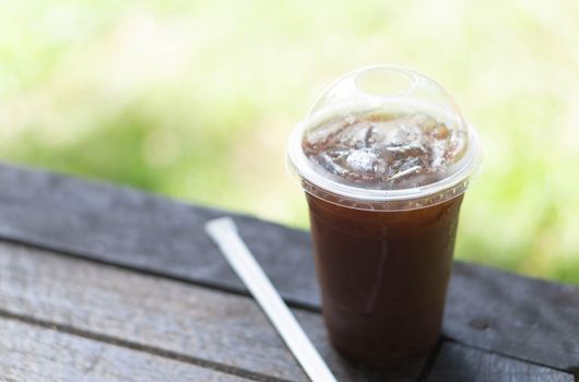 Close up glass of ice americano coffee on wood table, selective focus