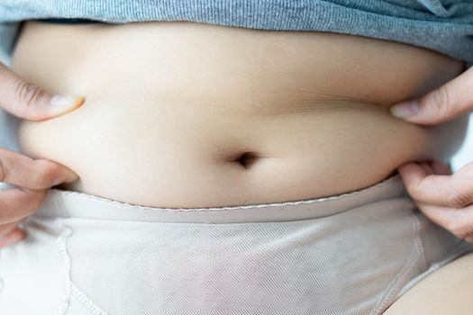 Closeup hand holding abdominal surface woman fat, healthy care and beauty concept