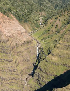 Aerial view of Waimea Canyon waterfall and landscape of hawaiian island of Kauai from helicopter flight