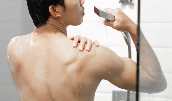 Closeup handsome asian man taking a shower in the bathroom, selective focus