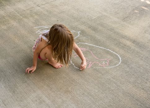 Small preschool girl drawing a chalk circle around the outline of an animal such as a cat or dog on concrete driveway