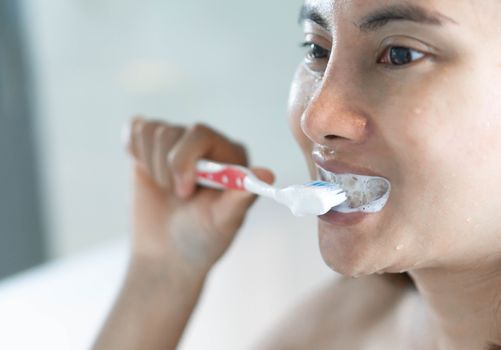 Closeup woman brushing teeth in the bathroom, health care concept