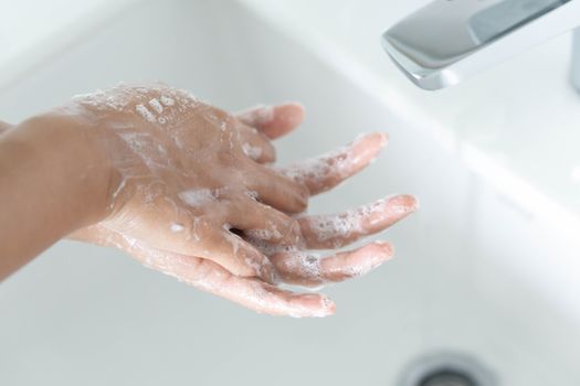 Closeup woman's hand washing with soap in bathroom, selective focus