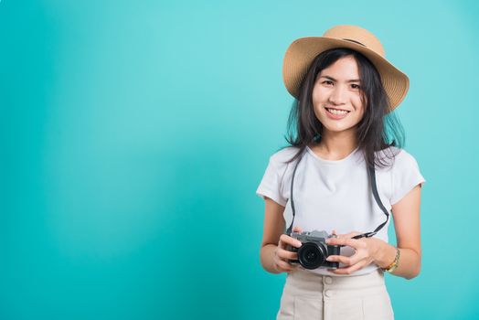 Traveler tourist happy Asian beautiful young woman smile in summer hat standing with mirrorless photo camera, shoot photo in studio on blue background with copy space for text