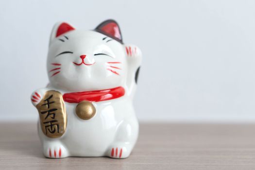 Maneki neko on wood table background, select focus