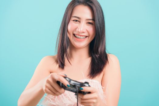Asian happy portrait beautiful young woman standing smile lifestyle games technology her holding joystick game playing on-hands on blue background with copy space for text