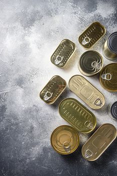 Various closed canned food, fish , fruits, vegetables, meat, soup different types of shapes top view on grey rustic background top view concept space for text