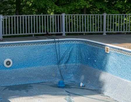 Empty in ground swimming pool ready for replacement of old vinyl lining or liner