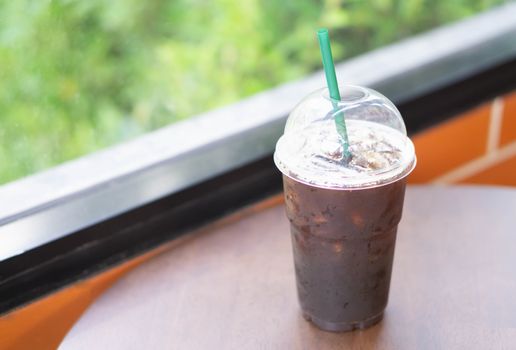 Close up glass of ice americano coffee on wood table in coffee shop, selective focus