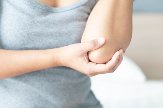 Closeup woman hand holding elbow with pain lying on bed, health care and medical concept