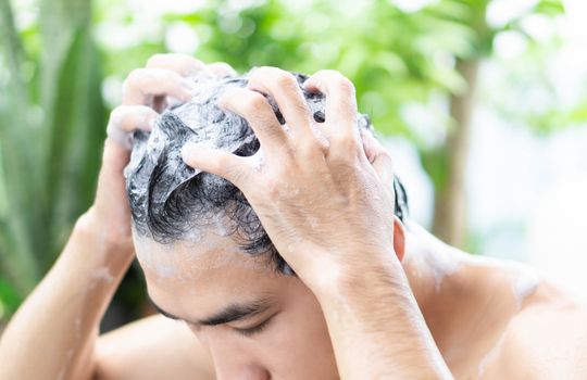Closeup young man washing hair with shampoo from outdoor, health care concept, selective focus