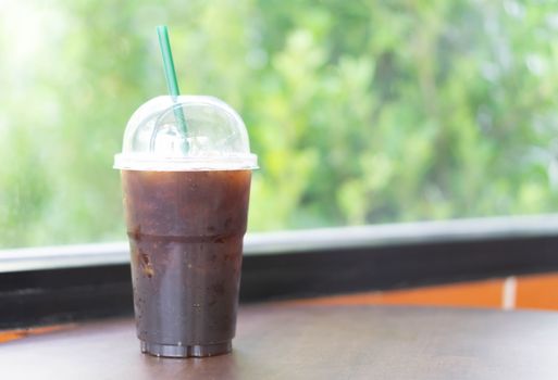 Close up glass of ice americano coffee on wood table in coffee shop, selective focus