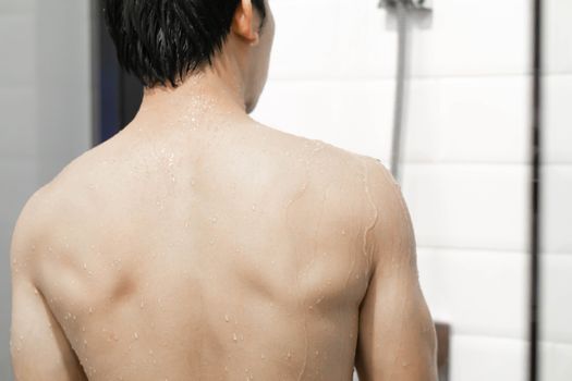 Closeup handsome asian man taking a shower in the bathroom, selective focus