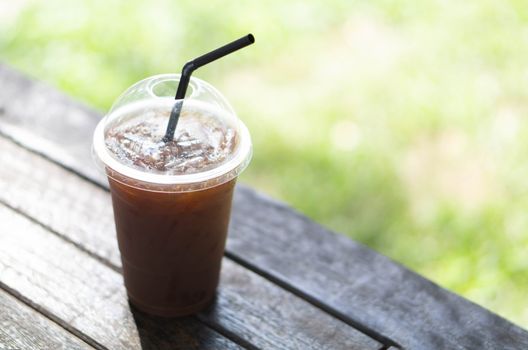 Close up glass of ice americano coffee on wood table, selective focus