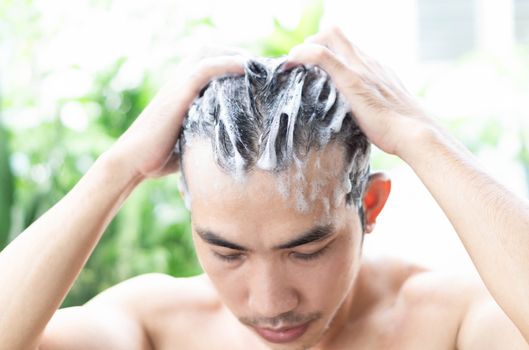 Closeup young man washing hair with shampoo from outdoor, health care concept, selective focus