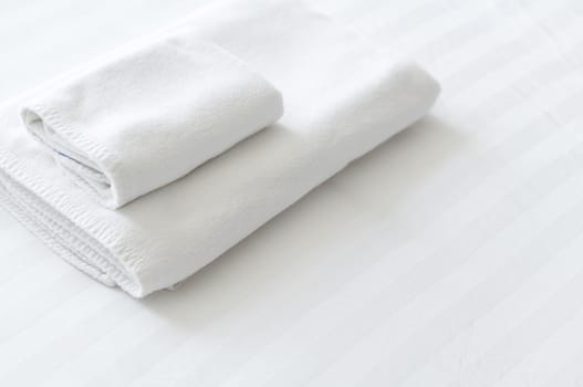 Closeup new towel on white bed with copy space
