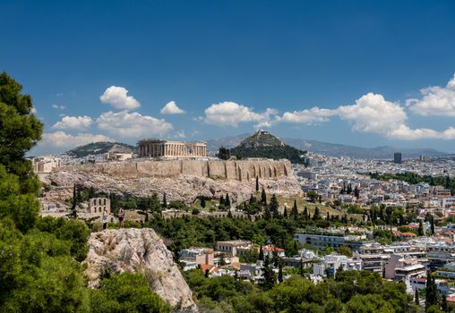 Acropolis and Lycabettus Hill framed by trees from the summit of Lycabettus hill
