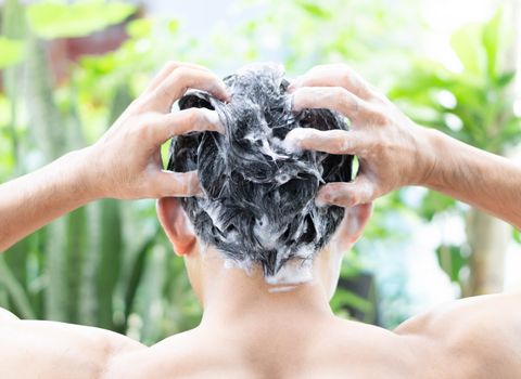 Closeup young man washing hair with shampoo from outdoor, health care concept, selective focus