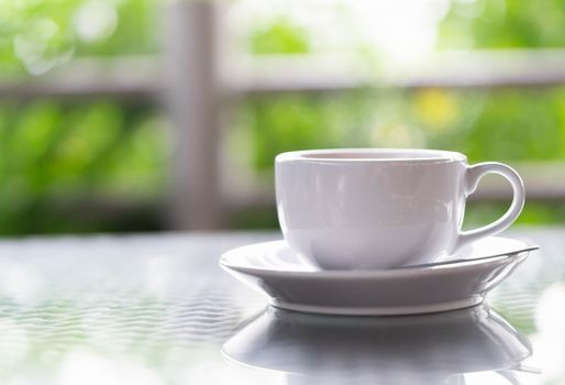 Closeup hot americano coffee on glass table with green nature background