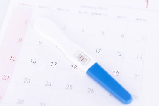 Closeup pregnancy test on calendar background, health care concept, selective focus