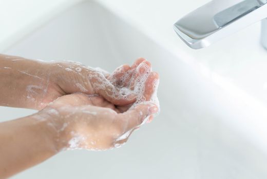 Closeup woman's hand washing with soap in bathroom, selective focus