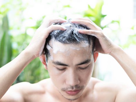 Closeup young man washing hair with shampoo from outdoor, health care concept, selective focus