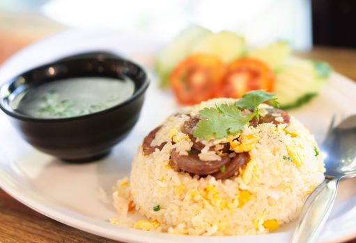 Closeup fired rice with sausage and vegetable in plate on wood table